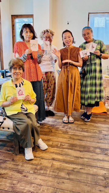 画像 絵を持った女性たちの写真 キャメルのワンピース